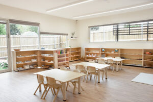 Childcare Montessori Preschool Classroom with open shelving, desks and chairs, and Montessori materials.