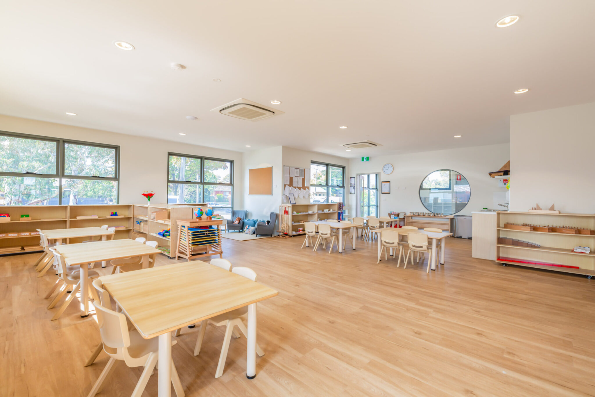 Childcare Montessori Preschool Classroom with open shelving, desks and chairs, and Montessori materials.