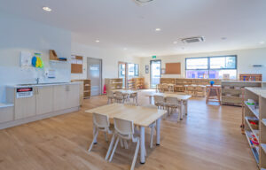 Childcare Montessori Preschool Classroom with open shelving, desks and chairs, and Montessori materials.