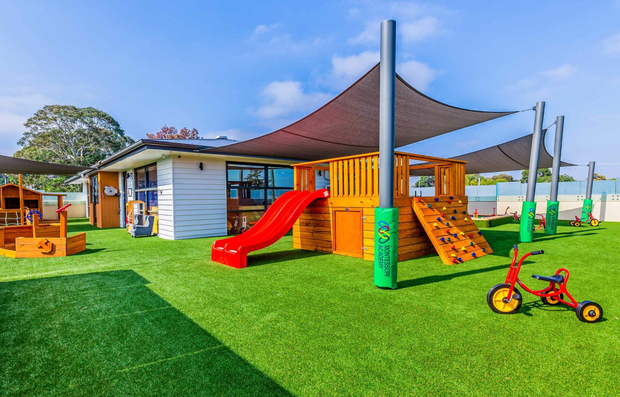 Childcare outdoor playground with play equipment, tricycles, shade sails and sandpit