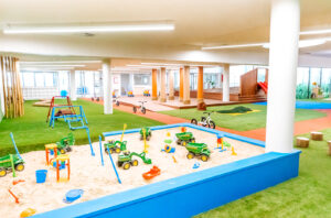 Childcare Outdoor Simulated Area with sandpit, bike track with tricycles, climbing frame, and slides.