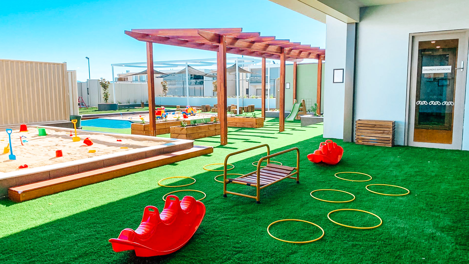 Childcare outdoor playground with hula hoops, sandpits and gardening beds.