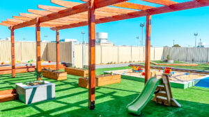 Childcare outdoor playground with sandpits, slide and gardening beds.