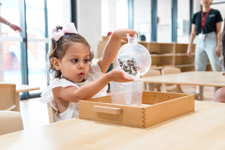 Child with bow pouring bells from a plastic jug into another