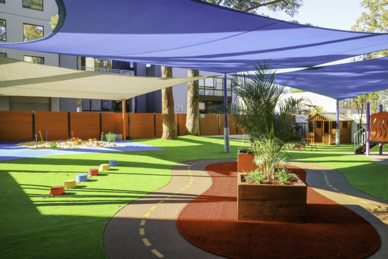 Outdoor play area at Montessori Academy’s Entrada childcare in Parramatta, with turfed play areas, a sandpit and bike track.