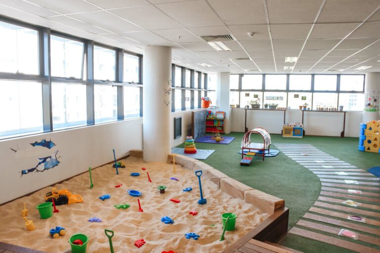 Indoor playground at Montessori Academy’s Bankstown childcare, with a sand pit and large turfed play areas.