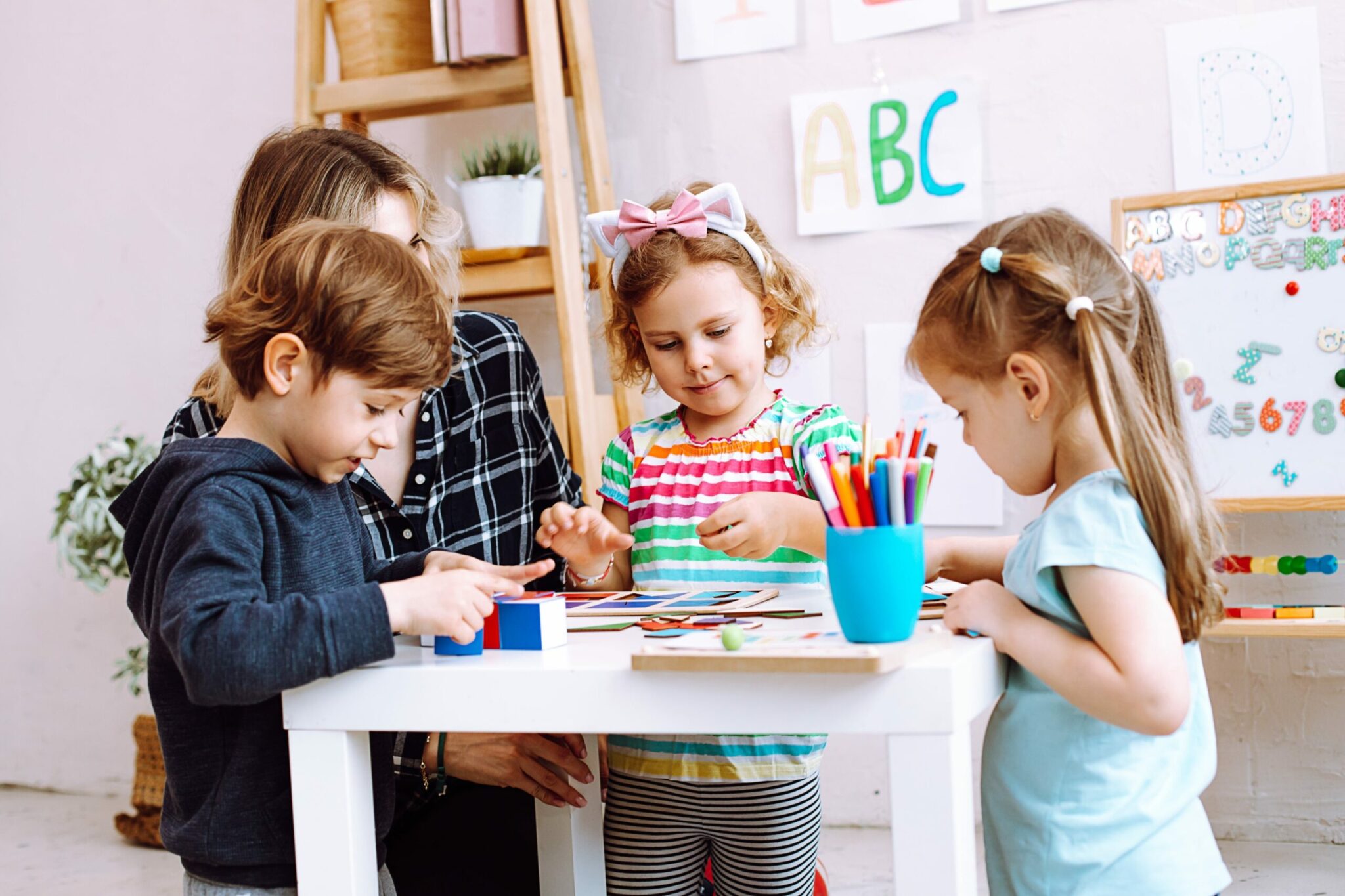 Three Children playing with preschool toys with a childcare worker.