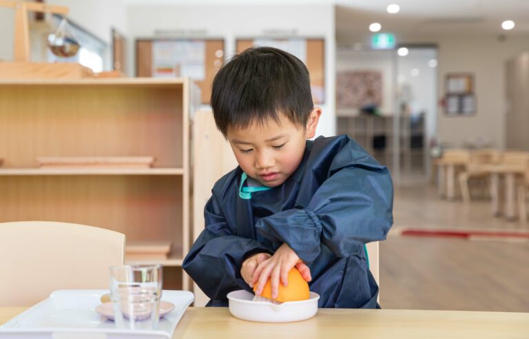 Young boy juicing an Orange in classroom