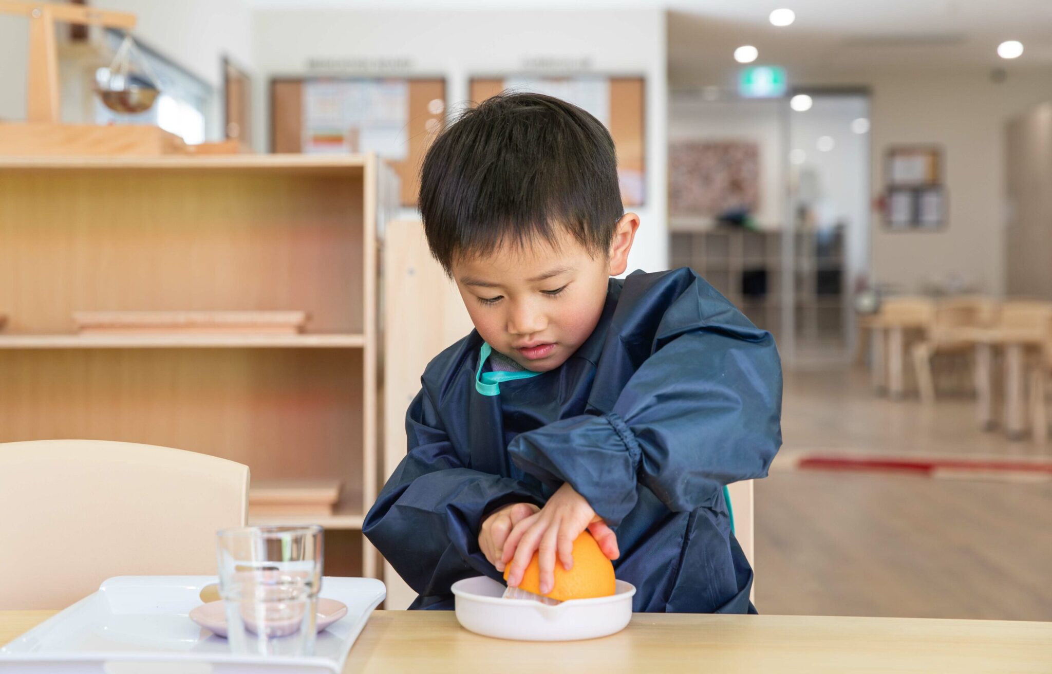 Young boy juicing an Orange in classroom