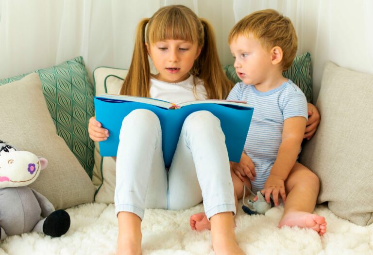 Young girl reading a book to younger boy in cosy corner
