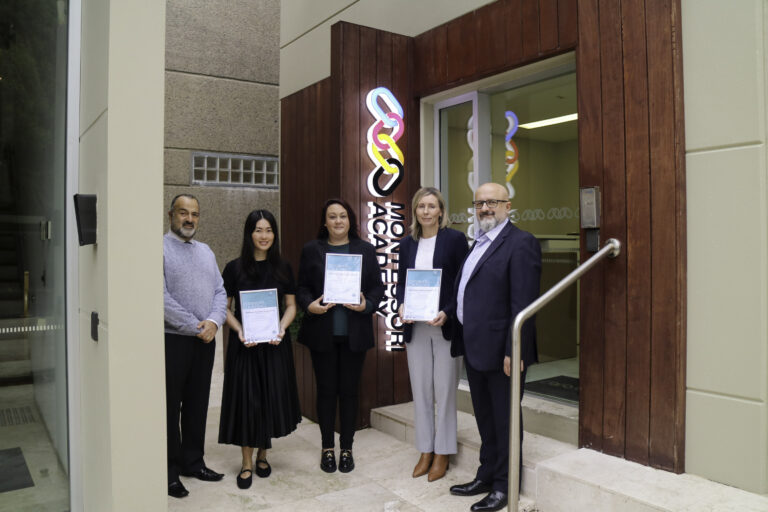 A diverse team of senior leaders stand in front of a Montessori Academy logo