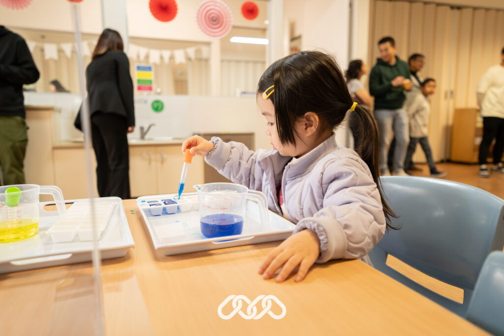 Child enjoys Montessori Eye Dropper activity at Auburn open day event.
