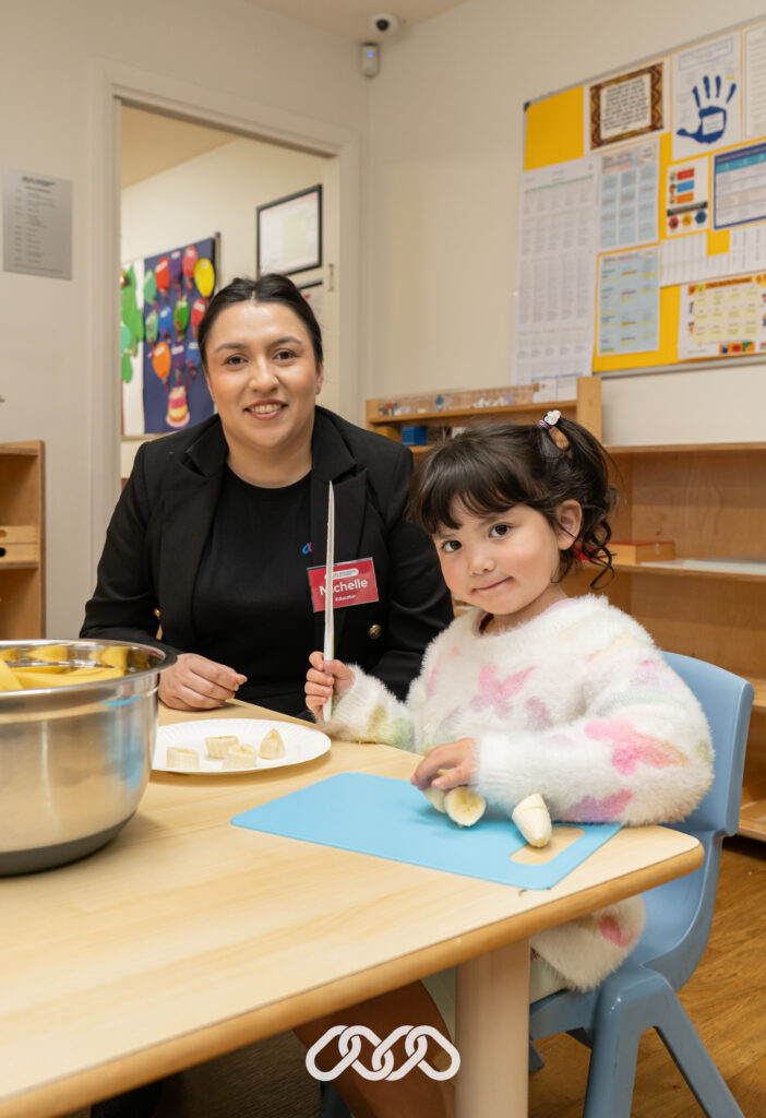 Educator and child working with banana cutting - a Montessori practical life activity